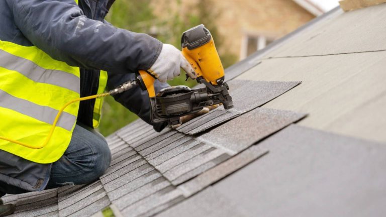 Contractor adding asphalt shingles to a roof.