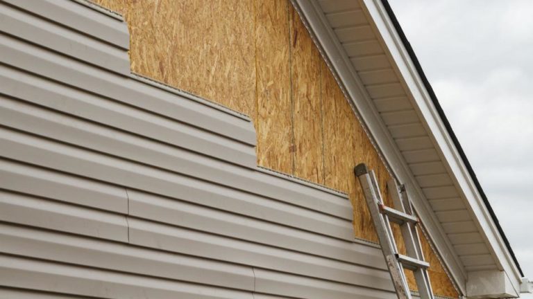 Ladder against exterior wall with some siding.