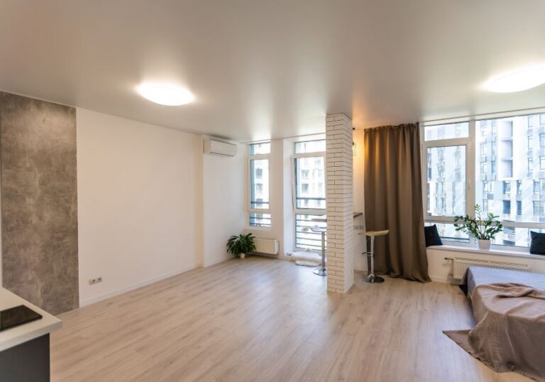 Residential bedroom restored with white walls, wood flooring and large windows.