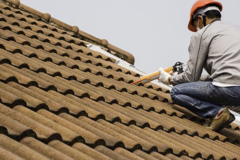 Man on roof placing tile shingles.