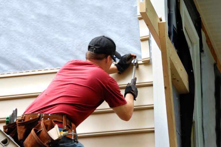 Man hanging siding on a house.