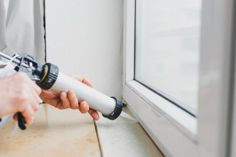 Caulk being applied to the bottom of a residential window.