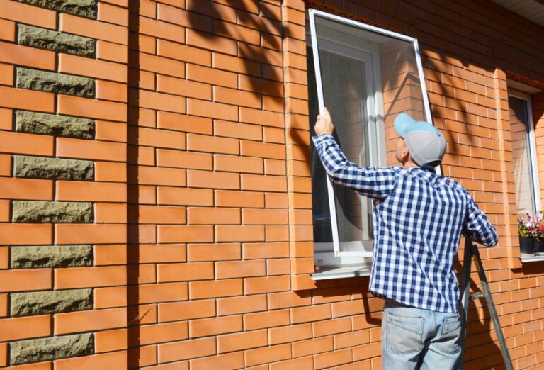 Man putting a screen on a residential window.