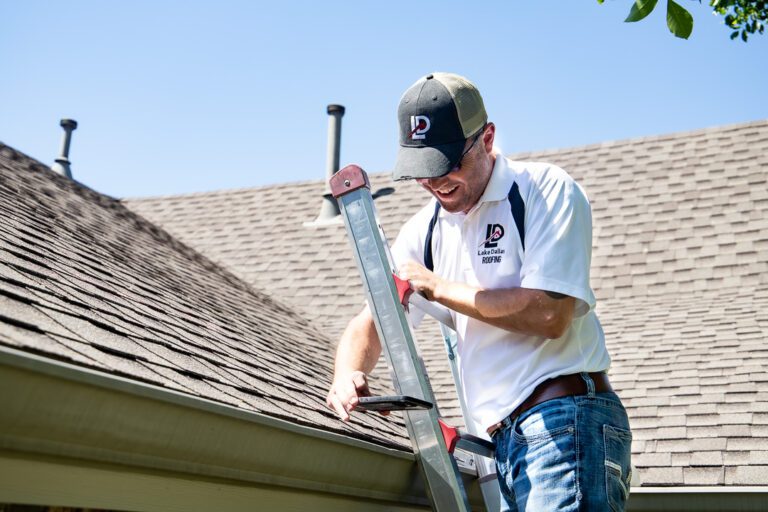 Tony, owner of Lake Dallas Roofing & Restorations, on a ladder inspecting a residential gutter.